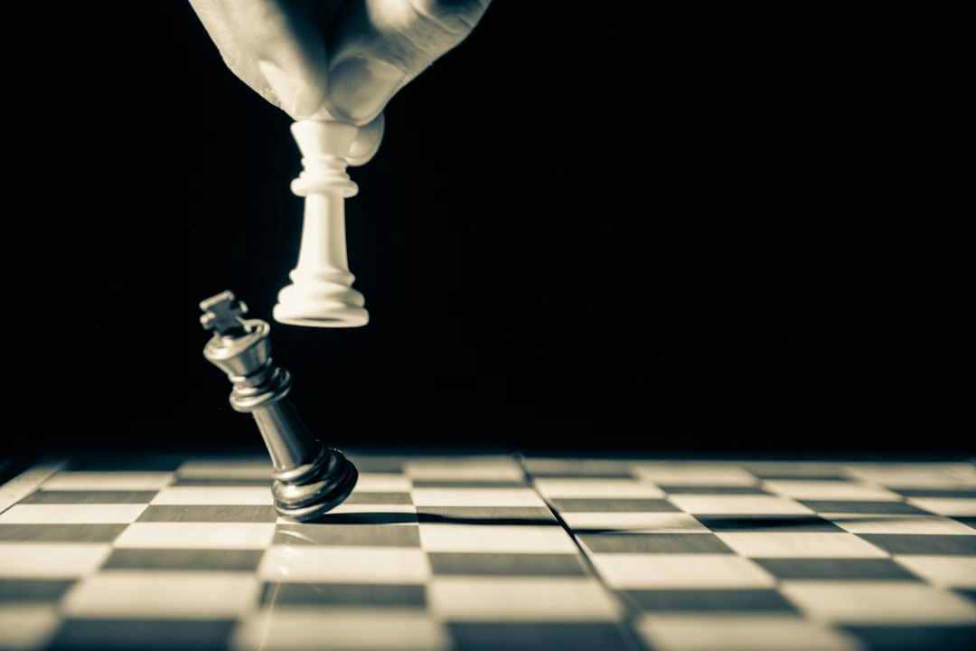 黑白棋盘上，一只手正推倒王